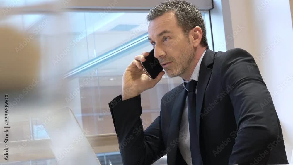 Businessman in modern office talking on phone Businessman in modern office talking on phone