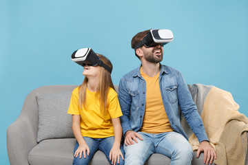 Funny bearded man in casual clothes with cute child baby girl. Father little daughter isolated on pastel blue background. Love family parenthood childhood concept. Sit on couch watching in headset.