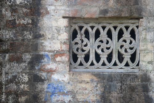 Beautiful vintage ancient old carved window with glass with a forged frame arches and patterns. The background.