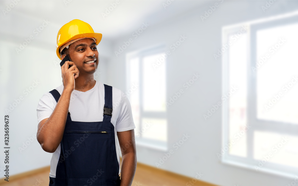 profession, construction and building - happy smiling indian worker or builder in helmet calling on smartphone over empty room at new home or apartment background profession, construction and building - happy smiling indian worker or builder in helmet calling on smartphone over empty room at new home or apartment background