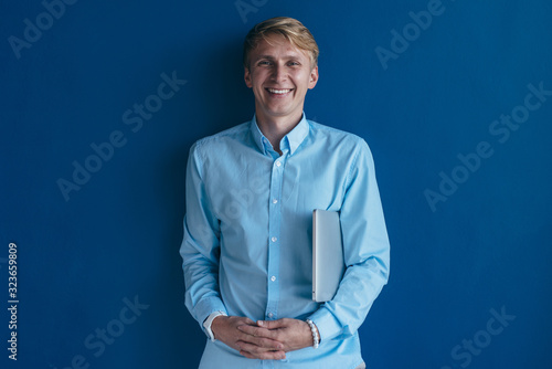 Photos Portrait of young man smiling and standing against blue background