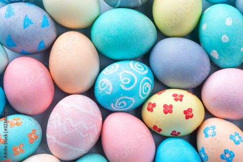 Fototapeta Colorful Easter eggs dyed by colored water with beautiful pattern on a pale blue background, design concept of holiday activity, top view, full frame