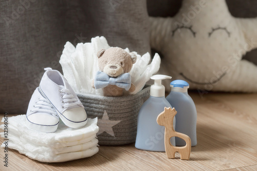 Fotografie A stack of diapers, sneakers, a bow tie and baby accessories on a wooden table