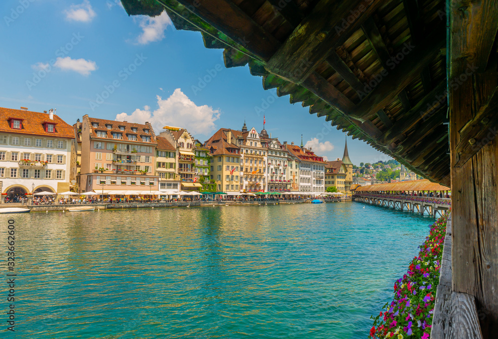 Chapel Bridge With Flowers and Luxury Hotel in City of Lucerne and Reuss River in Switzerland.