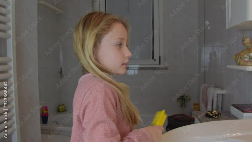 cute blonde young schoolgirl in a pink shirt combs hair cute blonde young schoolgirl in a pink shirt combs hair