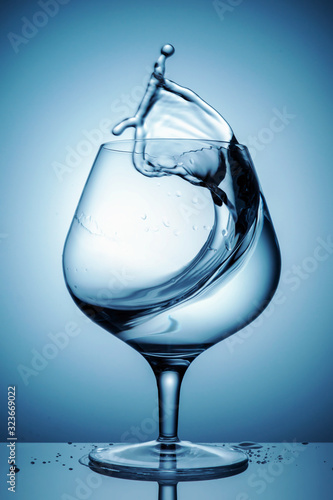 Single wineglass with transparent alcohol and splashes