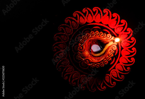 Glowing single terracotta lamp in the dark on top of a rangoli design with copy space. festival of light concept photo