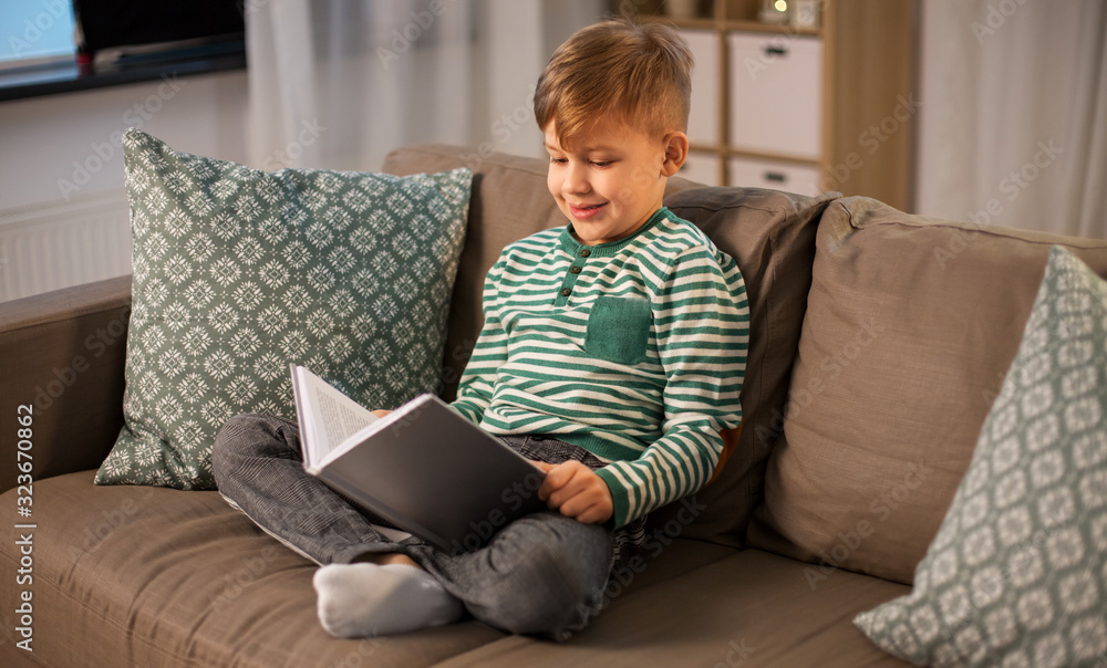 childhood and people concept - happy smiling little boy reading book at home childhood and people concept - happy smiling little boy reading book at home