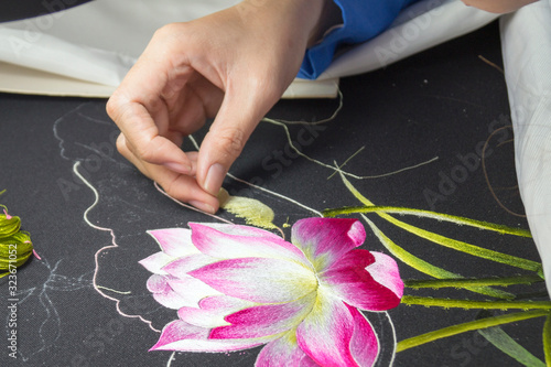 girl embroiders with colored thread on fabric