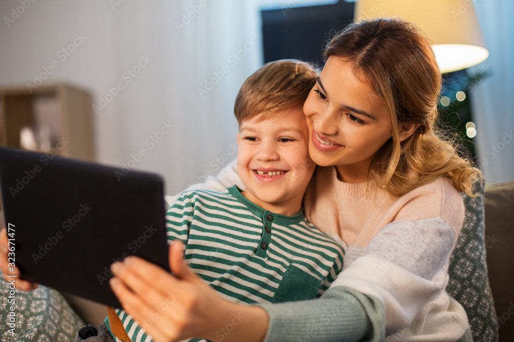 family, technology and people concept - happy mother and little son sitting on sofa and using tablet pc computer at home family, technology and people concept - happy mother and little son sitting on sofa and using tablet pc computer at home