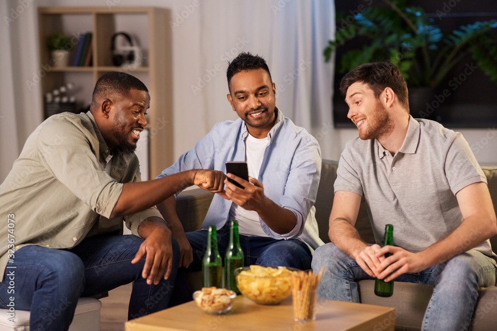 friendship, leisure and people concept - male friends with smartphone drinking beer at home at night friendship, leisure and people concept - male friends with smartphone drinking beer at home at night