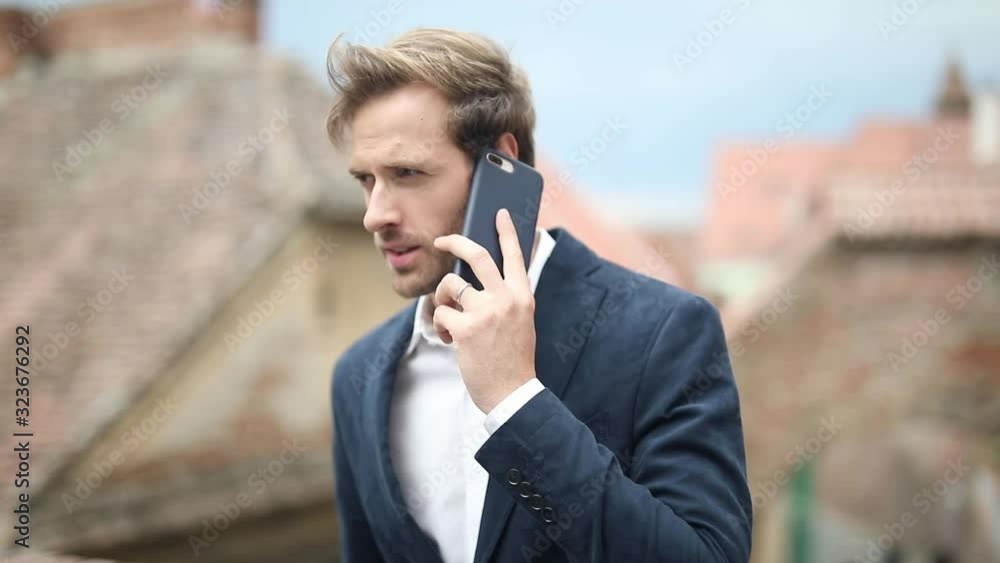 young casual man talking on the phone and then looking at the screen to read a new message young casual man talking on the phone and then looking at the screen to read a new message