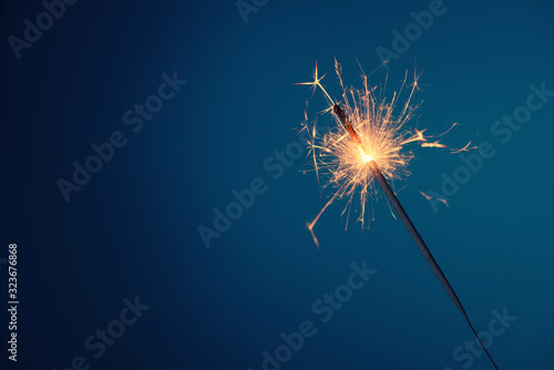 Bengal fire sparkler burning with sparks on blue background