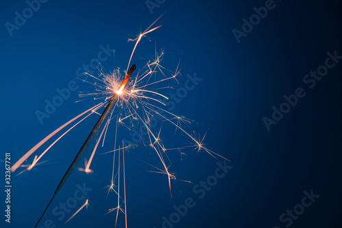 Bright burning sparkler bengal fire on blue background