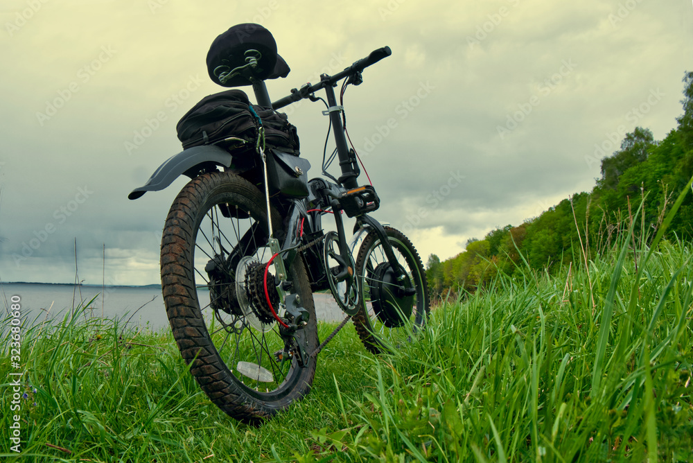 Electric bike on green grass in the background of a natural landscape.
