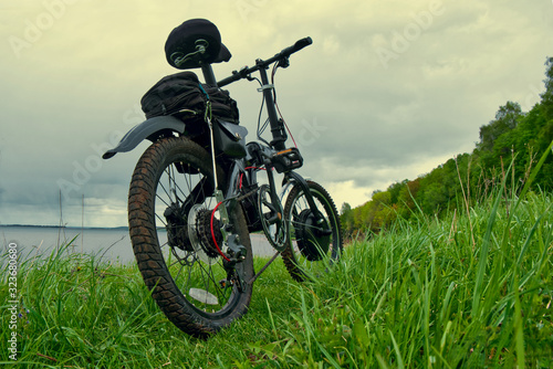 Electric bike on green grass in the background of a natural landscape.