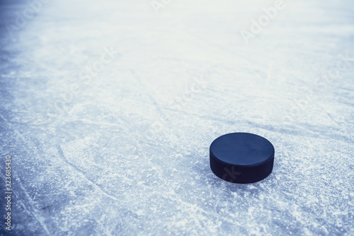 Photography black hockey puck lies on ice at stadium