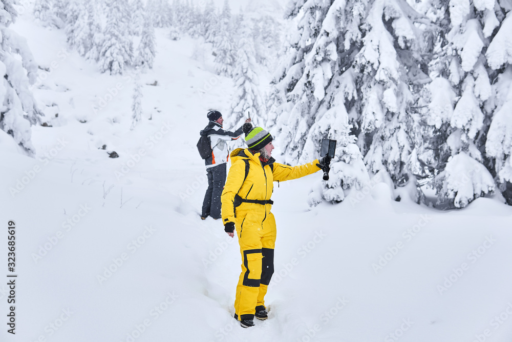 couple of travelers in a winter mountain forest take a selfie against the backdrop of the landscape