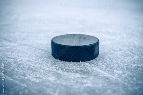 Photography hockey puck lies on the snow close-up