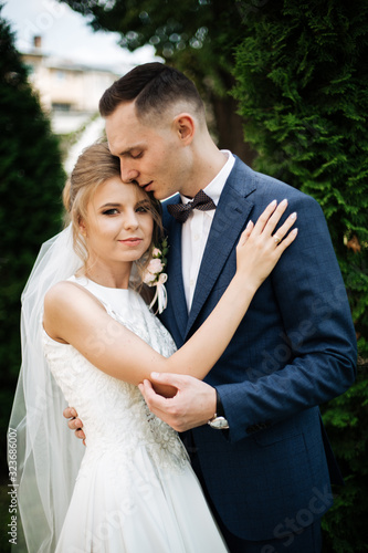 Happy bride and groom on their wedding. The groom kisses the forehead of the bride. Portrait of the bride. Newlyweds in the park. Happy couple. Wedding photo. Couple in love. © ostap_davydiak