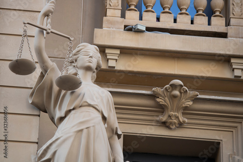 The statue of justice with a scales and a sword in his hand was carved out of stone.