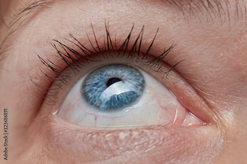 Close up of woman's eye with blue iris and looking up