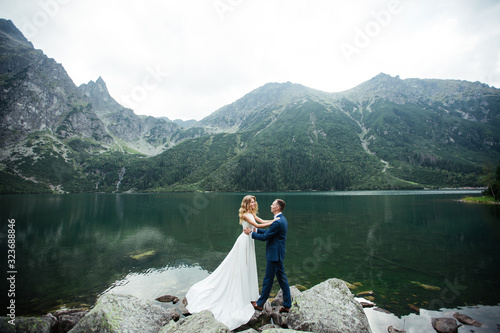 married couple (bride and groom) getting married in the mountains. hugging in the middle of a lake with a mountain in the background