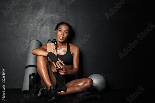 Image of young african american sportswoman with fitness equipment