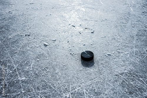 Photography black hockey puck lies on ice at stadium