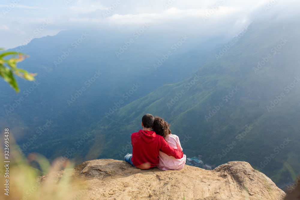 A guy with a girl cuddling with a beautiful view of the mountains. Romance in a picturesque place