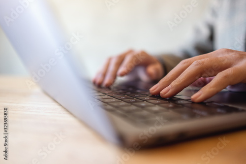 Closeup image of a woman working and typing on laptop computer keyboard on the table