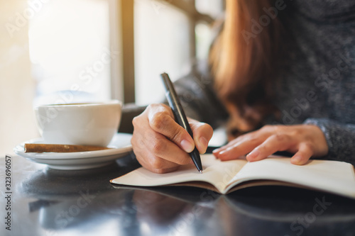 Closeup image of a woman writing on a blank notebook on the table