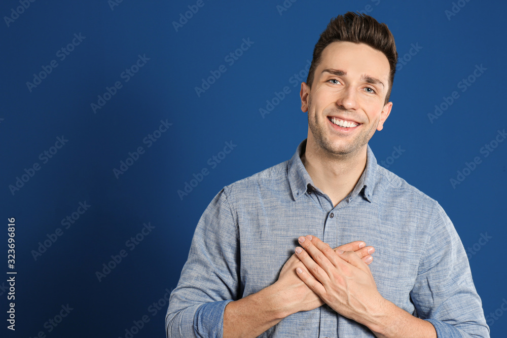 Handsome grateful man with hands on chest against blue background Handsome grateful man with hands on chest against blue background
