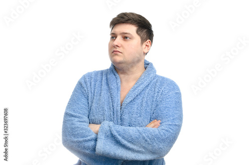Fat man stands thoughtfully in a blue bathrobe on a white background. isolate. copy space