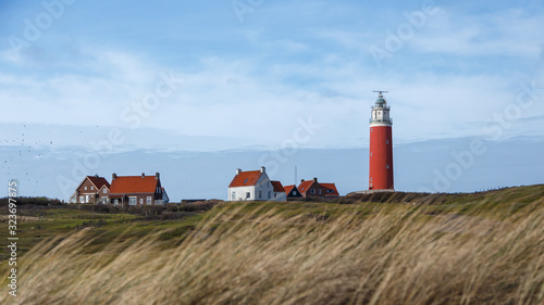 red lighthouse on an island with dunes