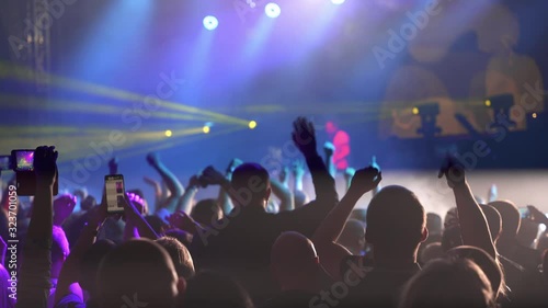 Happy people dance in nightclub party concert and listen to music from DJ on the stage in background. Music performance concert on stage photo