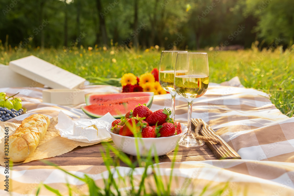 Romantic picnic in nature. The beauty of the setting sun, fresh fruits and wine.