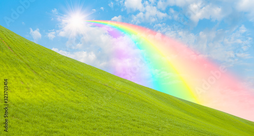Green grass field with rainbow and sun