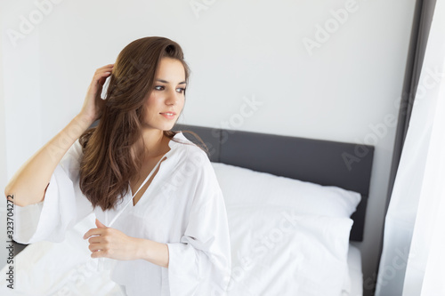 Woman enjoying morning awakening in a soft snow-white bed.