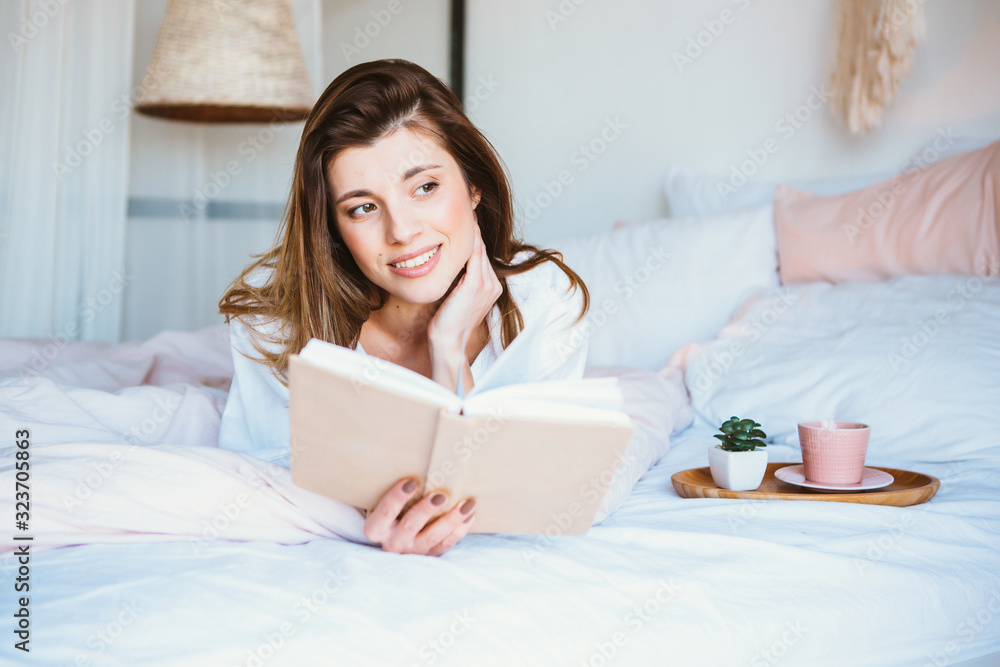 Girl reading a book, drinking coffee or tea, resting in bed. Girl reading a book, drinking coffee or tea, resting in bed.