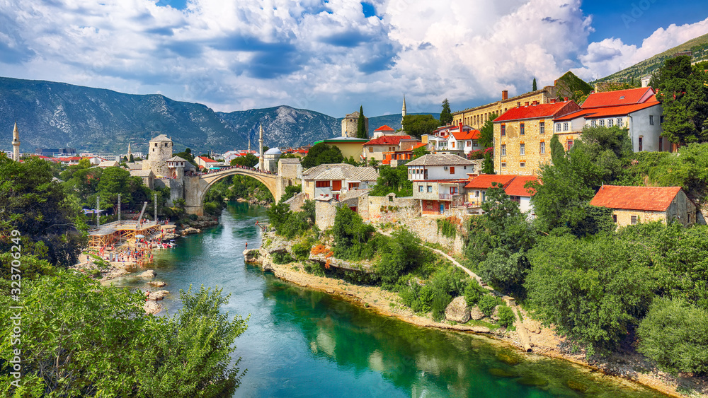 Fantastic Skyline of Mostar with the Mostar Bridge, houses and minarets, during sunny day.