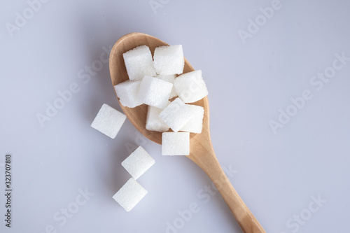 White sugar cube on wooden spoon. Flat view.