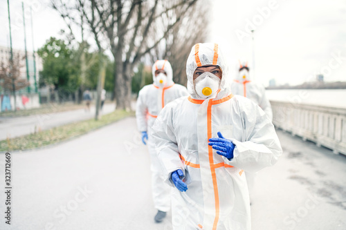 People with protective suits and respirators running outdoors, coronavirus concept.