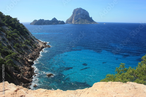 Fototapeta Naklejka Na Ścianę i Meble -  The island of Es Vedra between the blue sky and the blue sea of ​​the Ibizan coasts in front of the Cala D'Hort beach in the Balearic Islands