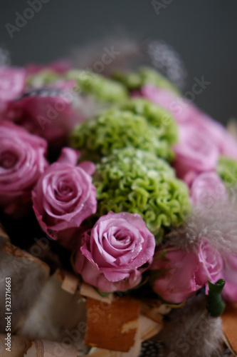 Beautiful spring bouquet close-up with pink roses and green carnations  decorated with feathers and birch bark. 