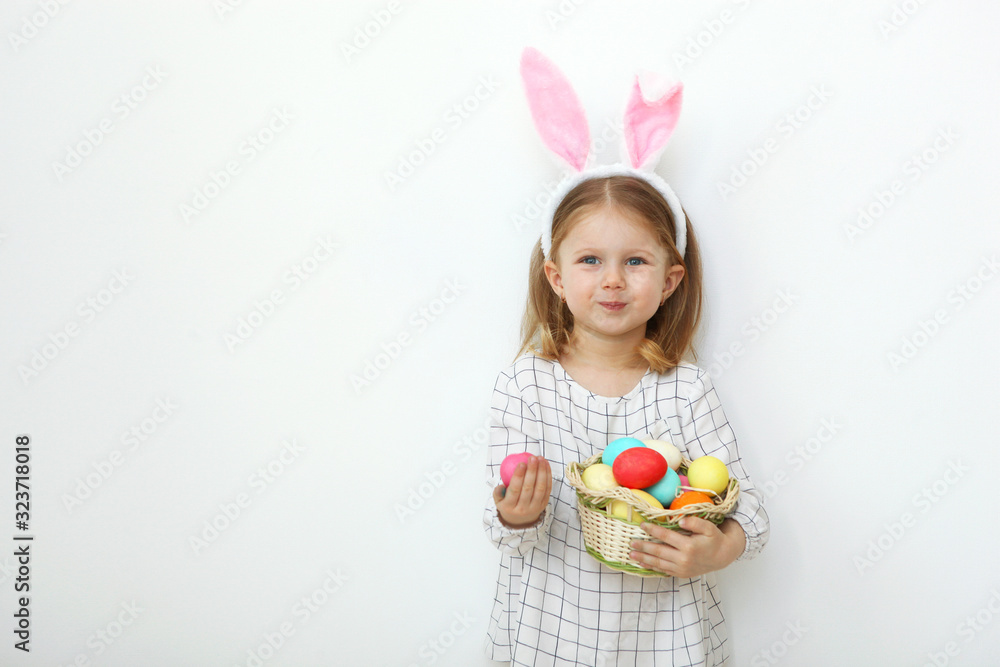 Cute little girl with easter basket on a light background. Place to insert text. Easter traditions. Happy easter! Cute little girl with easter basket on a light background. Place to insert text. Easter traditions. Happy easter!