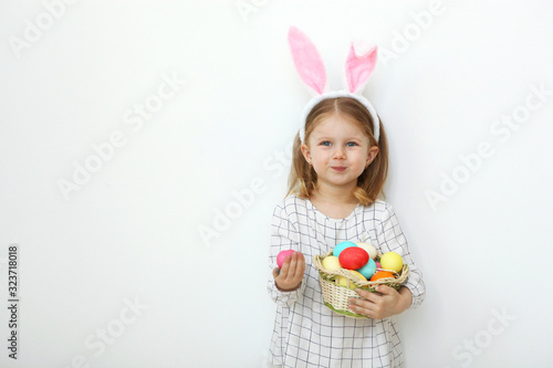Cute little girl with easter basket on a light background. Place to insert text. Easter traditions. Happy easter!