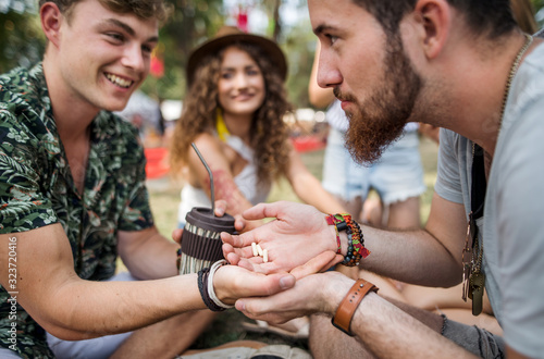 Canvas Print Group of young friends at summer festival, drug dealing concept.