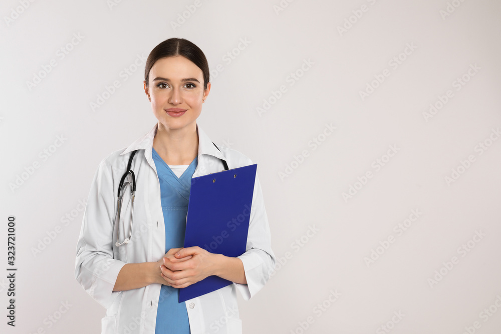 Doctor with stethoscope and clipboard on light grey background. Space for text Doctor with stethoscope and clipboard on light grey background. Space for text