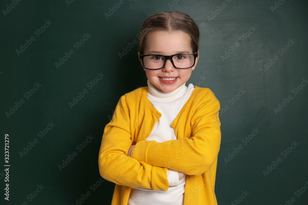 Cute little child wearing glasses near chalkboard. First time at school